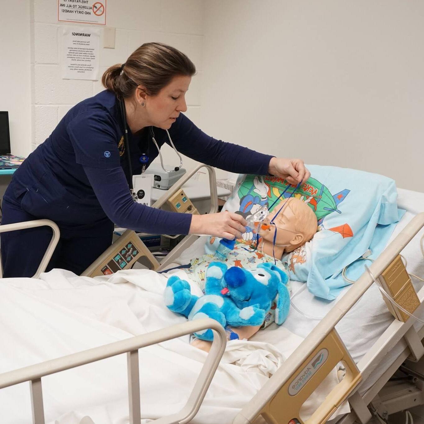 Nursing student putting a mask onto a training dummy